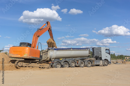 Excavator pushes the truck with a bucket
