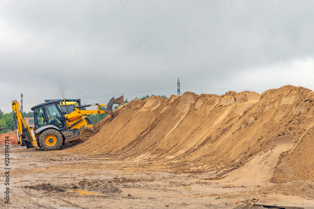 Bulldozer at a construction site forms a pile of sand Bulldozer at a construction site forms a pile of sand