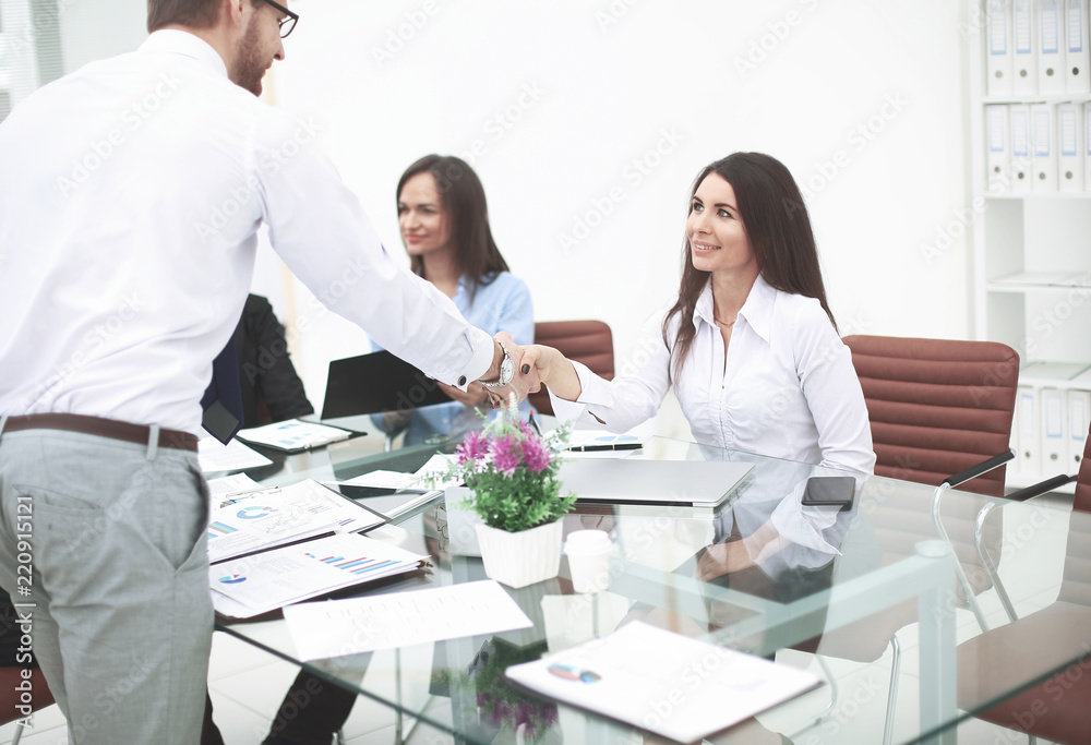 man and woman partners shaking hands over the table, maintaining eye contact man and woman partners shaking hands over the table, maintaining eye contact