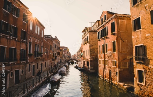Seen from a bridge of a classic Venice canal on a beautiful sunny day with a blue sky, the sun's rays beat on the historic buildings accentuating their color