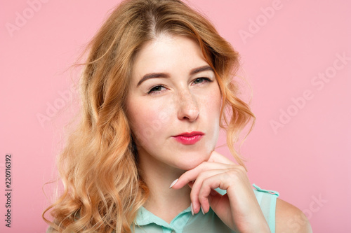 emotion expression. suspicious thoughtful dubious distrustful woman raising a brow. young beautiful girl portrait on pink background.