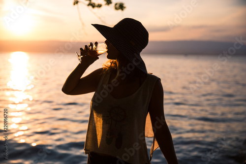 Silhouetted Woman Drinking a Glass of Rosé Wine and Wearing a See-through Summer T-Shirt at Sunset.