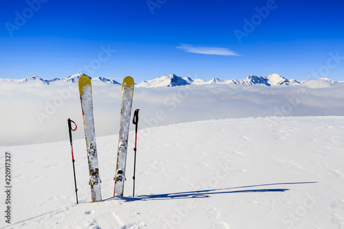 Narty w sezonie zimowym, góry i sprzęt narciarski na szczycie w słoneczny dzień we Francji, w Alpach ponad chmurami.