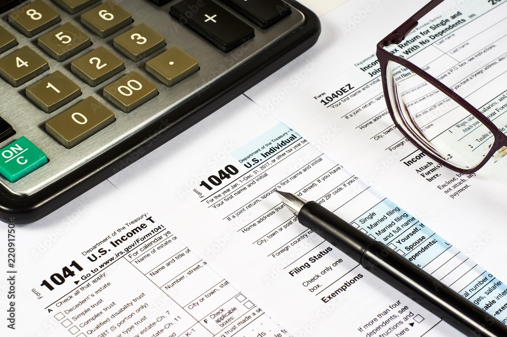 Tax Form 1040, 1041, 1040EZ and pen on a background of a calculator and glasses, close-up Tax Form 1040, 1041, 1040EZ and pen on a background of a calculator and glasses, close-up