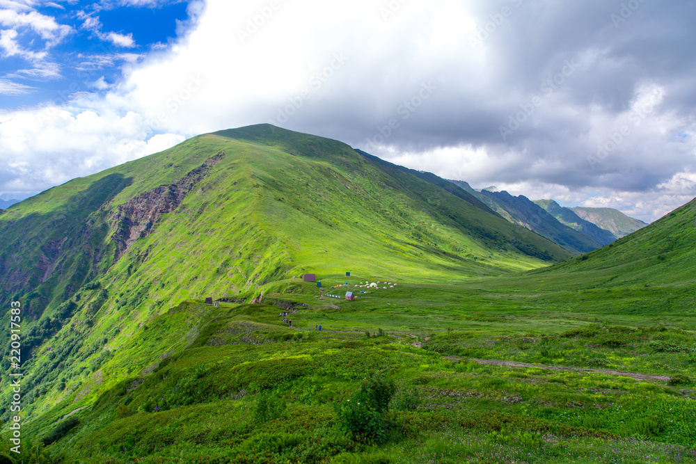 Panoramic view of Caucasian mountains with fresh green meadows in bloom on a beautiful sunny day,  Sochi, Russia
