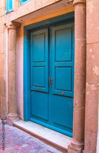 The old wooden door is blue in the background of the plastered peeling wall. Moroccan style. Africa, Morocco, Essaouira