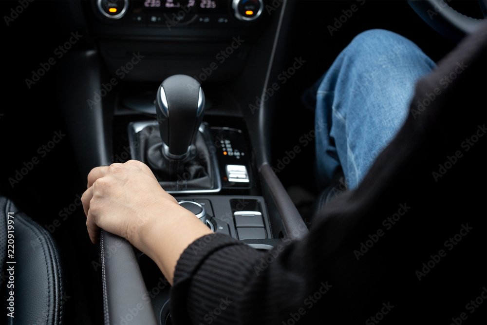 Woman driving a car with hand holding handbrake on a automatic g