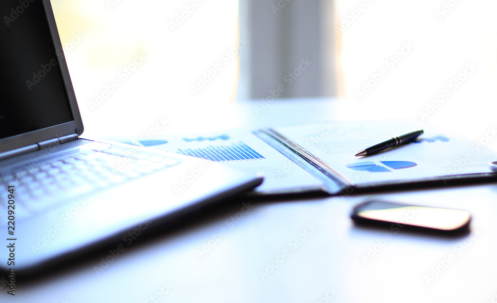 laptop,a financial schedule and a smartphone on the desktop