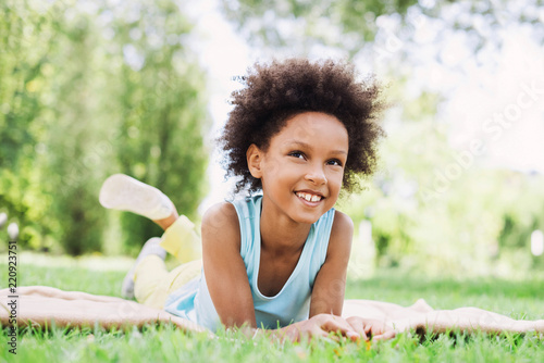 Beautiful kid girl lying down in a grass.  Healthy smiling little girl enjoying life.  Relaxing in nature, summer holidays concept