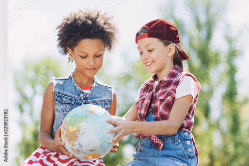 Happy little girls looking at globe, education or travel concept