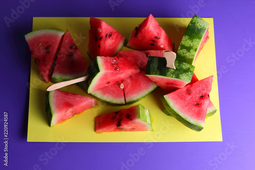 Watermelon pop art. Many pieces of watermelon on a yellow purple background. Natural dessert. Creative story with food for vegetarians. Healthy food