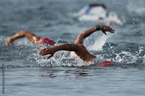 Swimmers swimming crawl in blue sea, contest triathlon