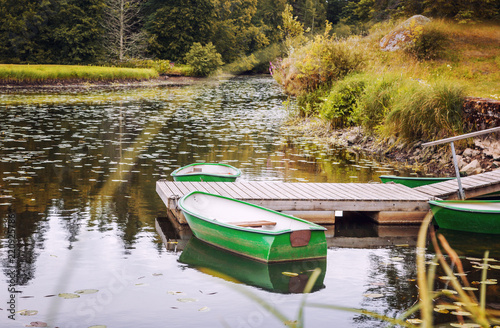 An old small wooden boat on the lake near the shore, a beautiful autumn landscape