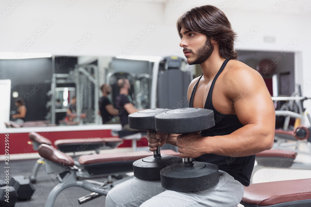 Bodybuilder lifting dumbbell weights in a gym Bodybuilder lifting dumbbell weights in a gym