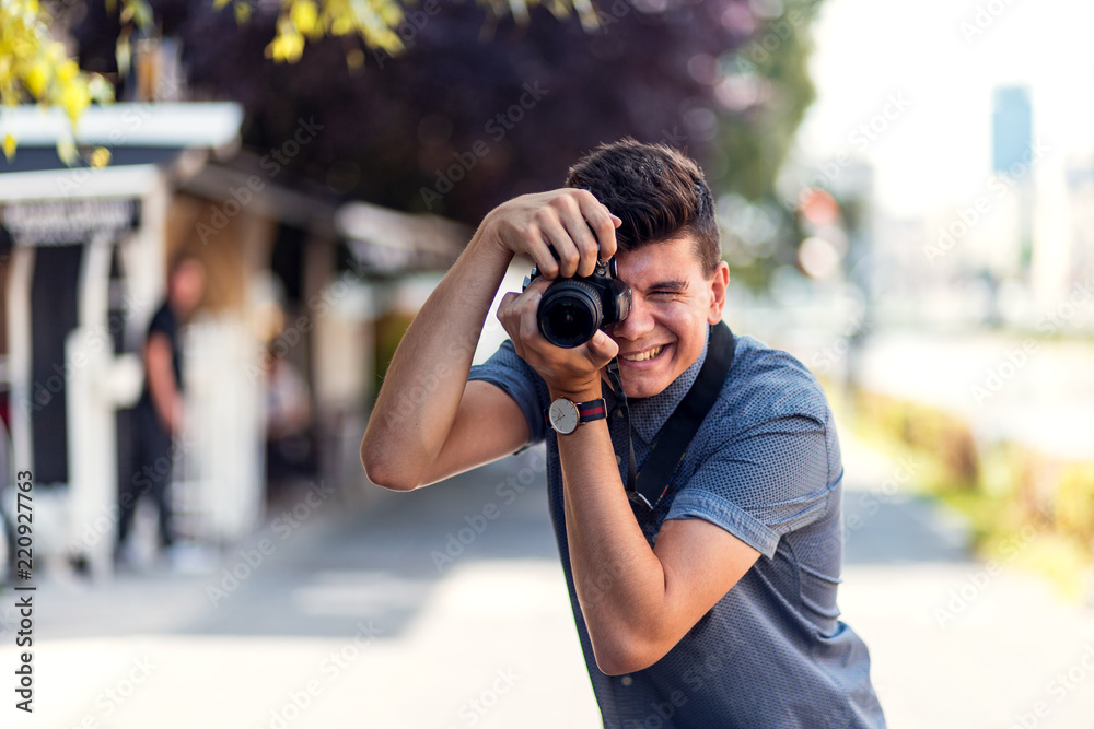 Young professional male photographer using camera at street