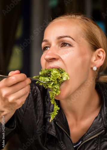 businesswoman eating salad in an outdoor cafe. Healthy lifestyle: girl eating green tasty food