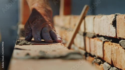 Construction of a new apartment house with their own hands, brick masonry by a senior man, close-up photo