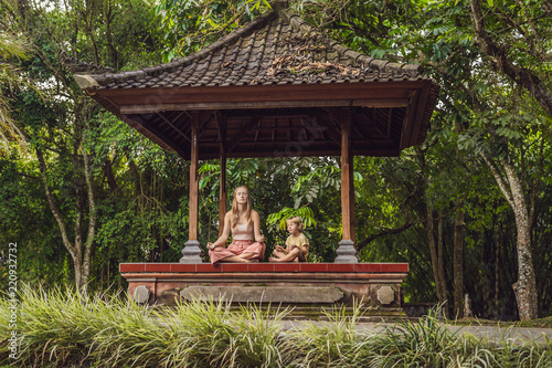 Mom and son meditate practicing yoga in the traditional balinesse gazebo photo