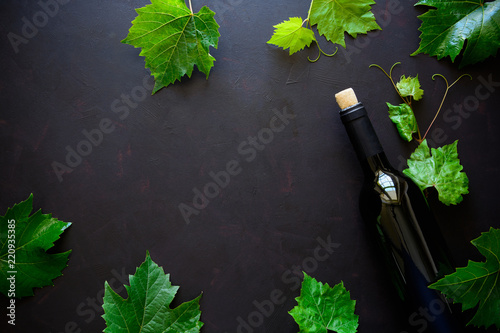 Bottle of red wine, grapes and leaves lying on dark wooden background. Top view. Flat lay. Copy space