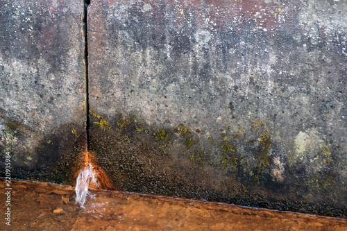 two concrete slabs of dirty gray color in spots, rusty water flows from the hole from below, in the foreground there is a liquid rusty from corrosion, a gloomy look, design, background, daylight,