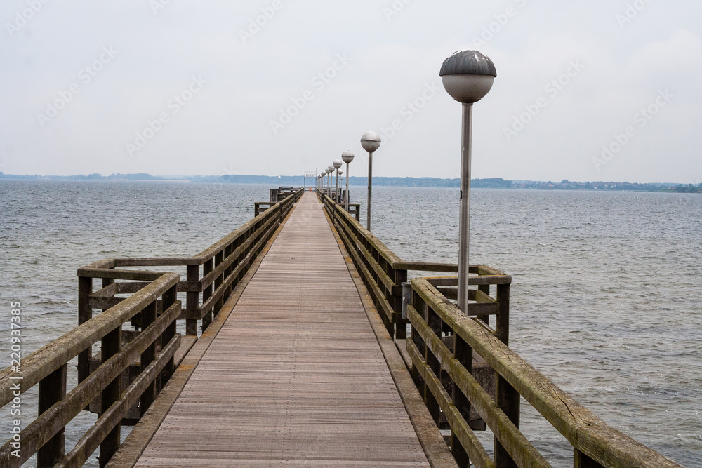 Holzbrücke an der Ostsee mit elektrischen Lampen und Gehweg