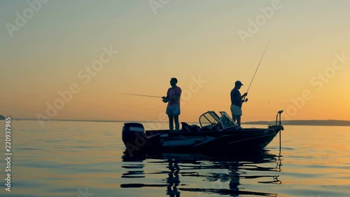 A man is casting a fishing rod while fishing with another man from an autoboat