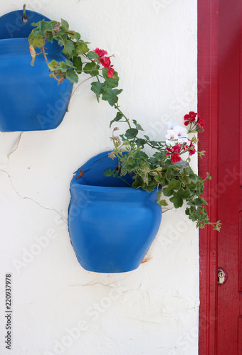 Two blue flower planters hanging on a white stone house facade on the mediterranean island Bozcaada in Turkey. © Anna