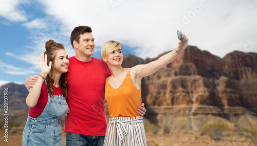 travel, tourism and summer holidays concept - group of happy smiling friends taking selfie by smartphone over grand canyon national park background © Syda Productions