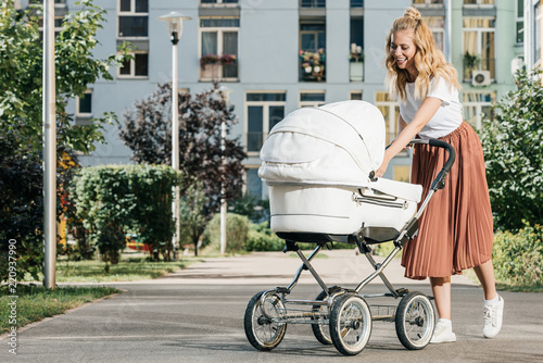 Fotografie mother walking and looking at baby stroller on street