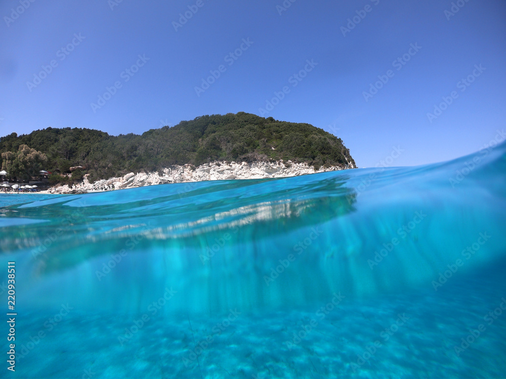 Underwater photo of tropical paradise turquoise exotic beach of Voutoumi with sail boats docked in island of Antipaxos, Ionian, Greece