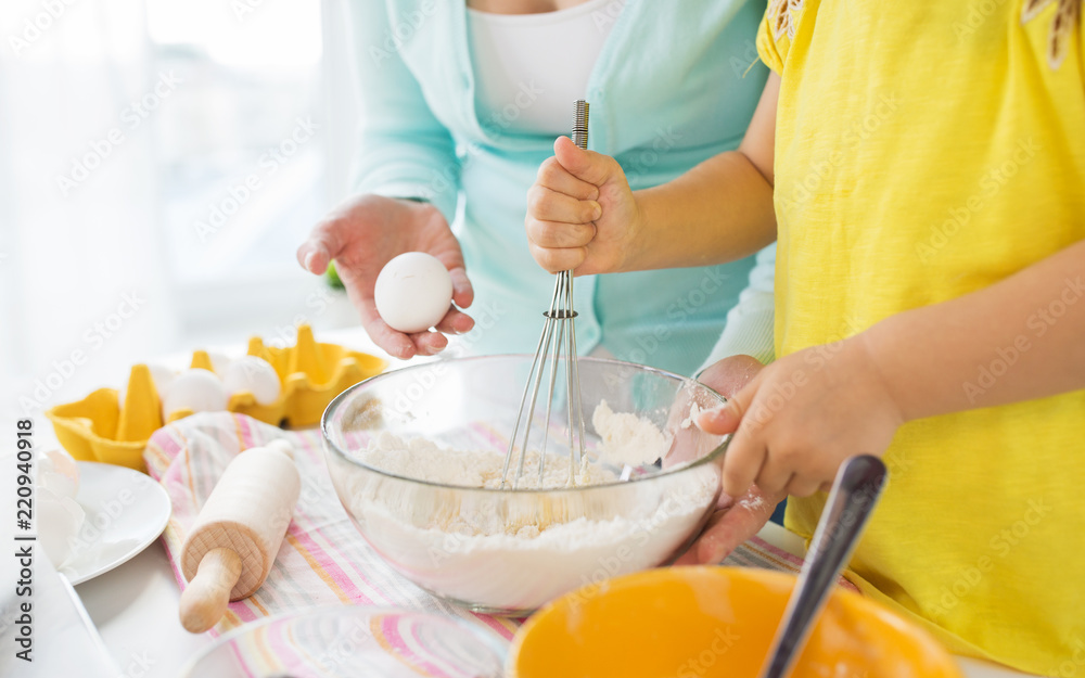 family, cooking, baking and people concept - close up of mother and little daughter with flour, eggs and whisk making dough at home kitchen