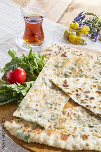 Typical Turkish meal Gozleme with herb and cheese on light wooden cutting board.