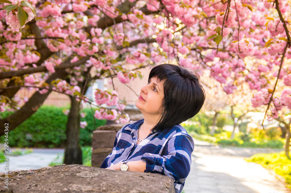 Portrait of middle-aged brunette woman in blooming sakura trees Portrait of middle-aged brunette woman in blooming sakura trees