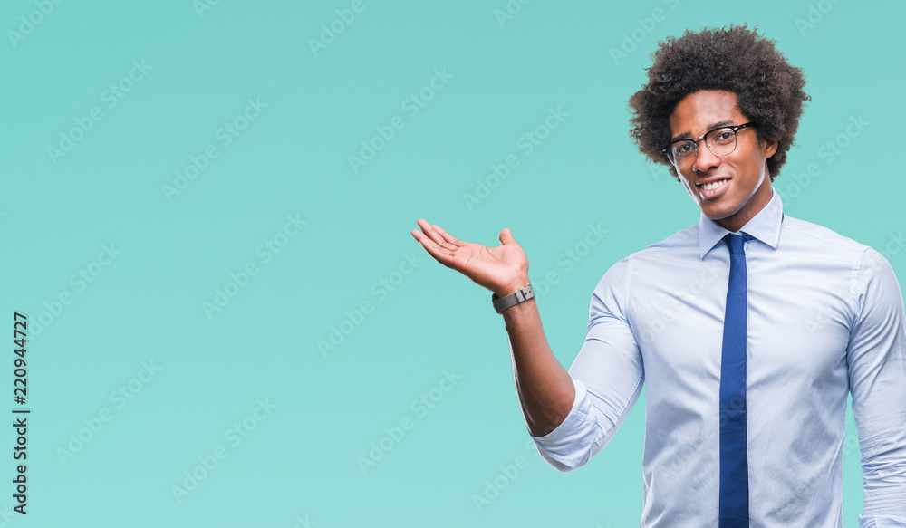 Afro american business man wearing glasses over isolated background smiling cheerful presenting and pointing with palm of hand looking at the camera. Afro american business man wearing glasses over isolated background smiling cheerful presenting and pointing with palm of hand looking at the camera.