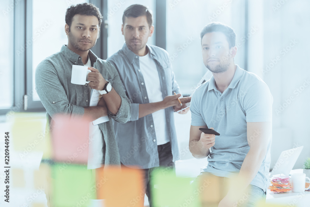 Fototapeta premium selective focus of young multiethnic businessmen looking at sticky notes while working at new project together
