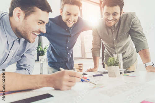 Three young businessmen leaning at table and working at project together, business teamwork concept