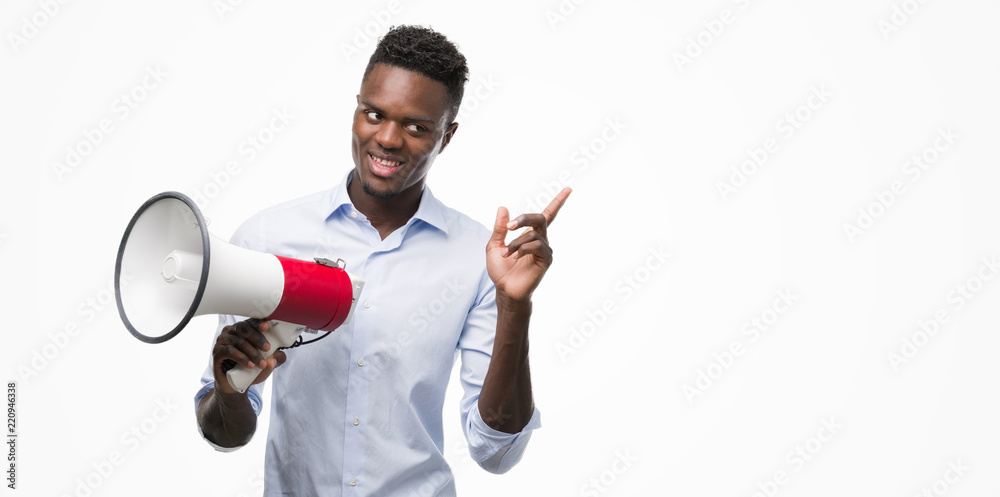 Young african american man holding megaphone very happy pointing with hand and finger to the side