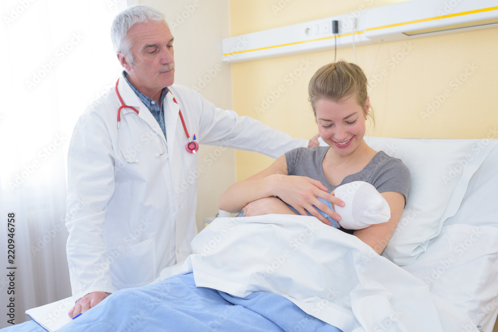 Doctor watching mother and newborn baby Doctor watching mother and newborn baby