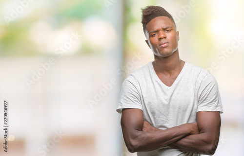 Young african american man over isolated background skeptic and nervous, disapproving expression on face with crossed arms. Negative person.