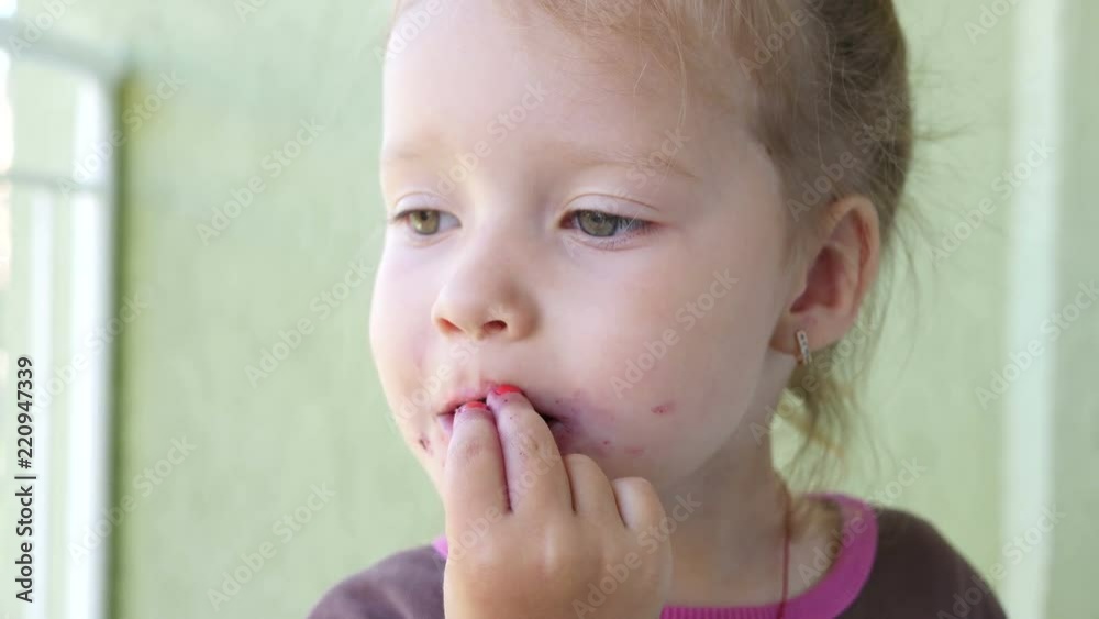 Child kid girl greedily eats a berry cherry stain get dirty face color Child kid girl greedily eats a berry cherry stain get dirty face color