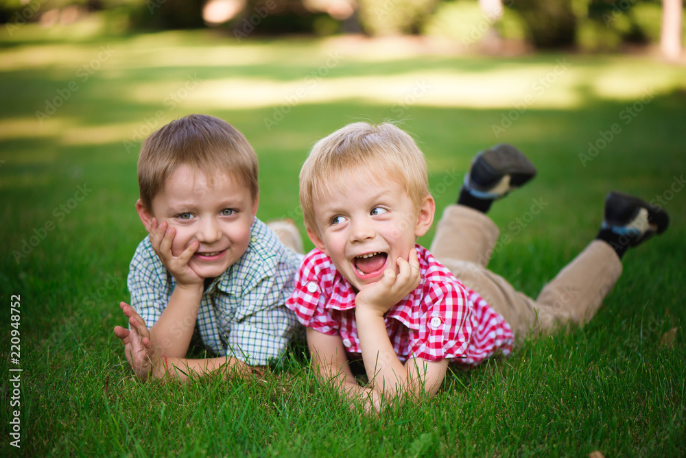 Two brothers lying on the grass in a park outdoors, smiling and Two brothers lying on the grass in a park outdoors, smiling and
