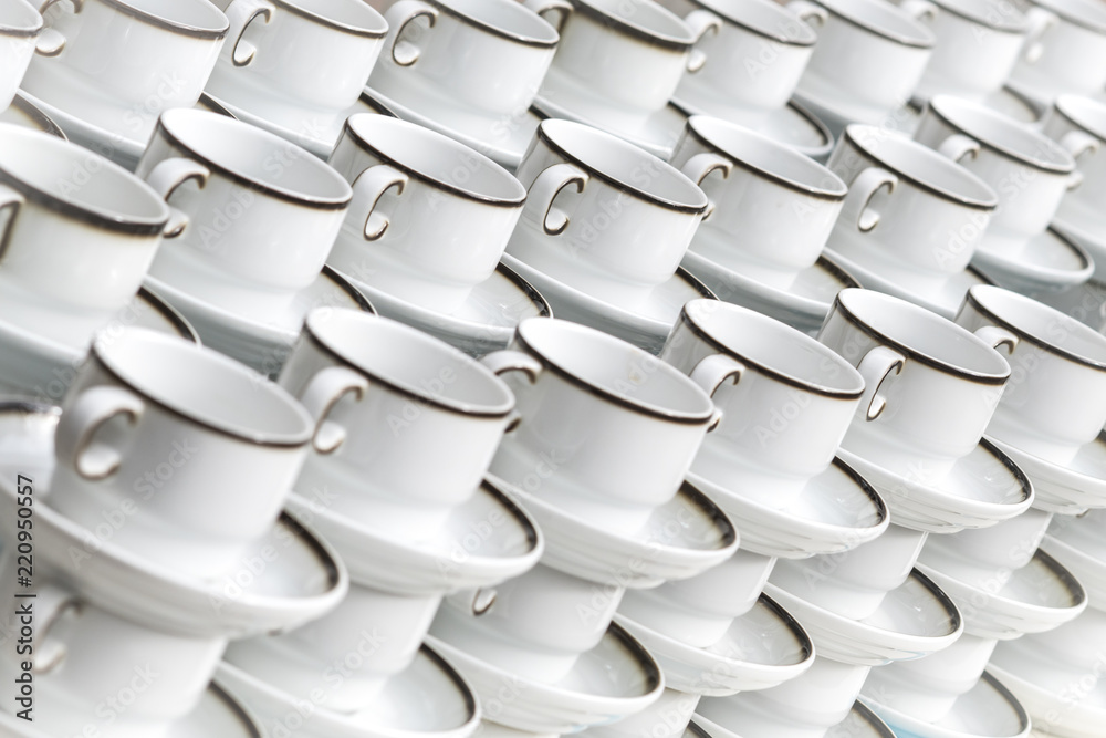 White coffee cups with plates stand stacked in a row