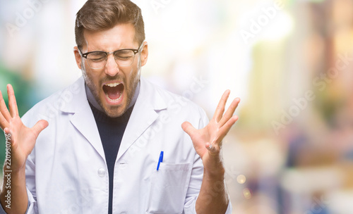 Young handsome man wearing doctor, scientis coat over isolated background celebrating mad and crazy for success with arms raised and closed eyes screaming excited. Winner concept © Krakenimages.com