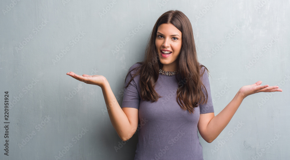 Young brunette woman over grunge grey wall very happy and excited, winner expression celebrating victory screaming with big smile and raised hands Young brunette woman over grunge grey wall very happy and excited, winner expression celebrating victory screaming with big smile and raised hands