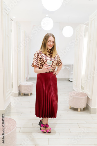 Weight loss, body image, self-esteem, shopping, fashion concept. Woman taking smartphone selfie in the mirror of outfit in changing room at upscale store or at home trying on clothing.