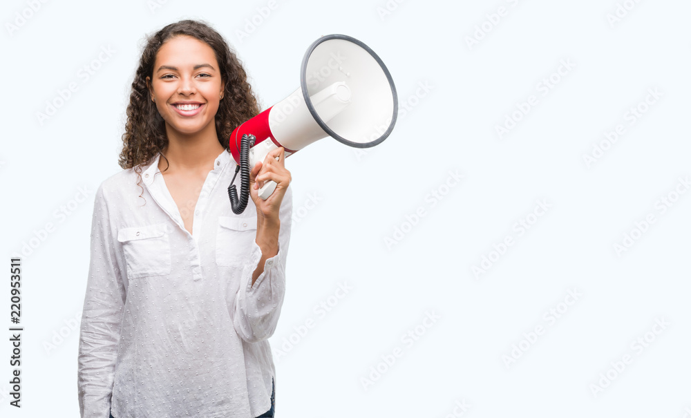 Young hispanic woman holding megaphone with a happy face standing and smiling with a confident smile showing teeth Young hispanic woman holding megaphone with a happy face standing and smiling with a confident smile showing teeth