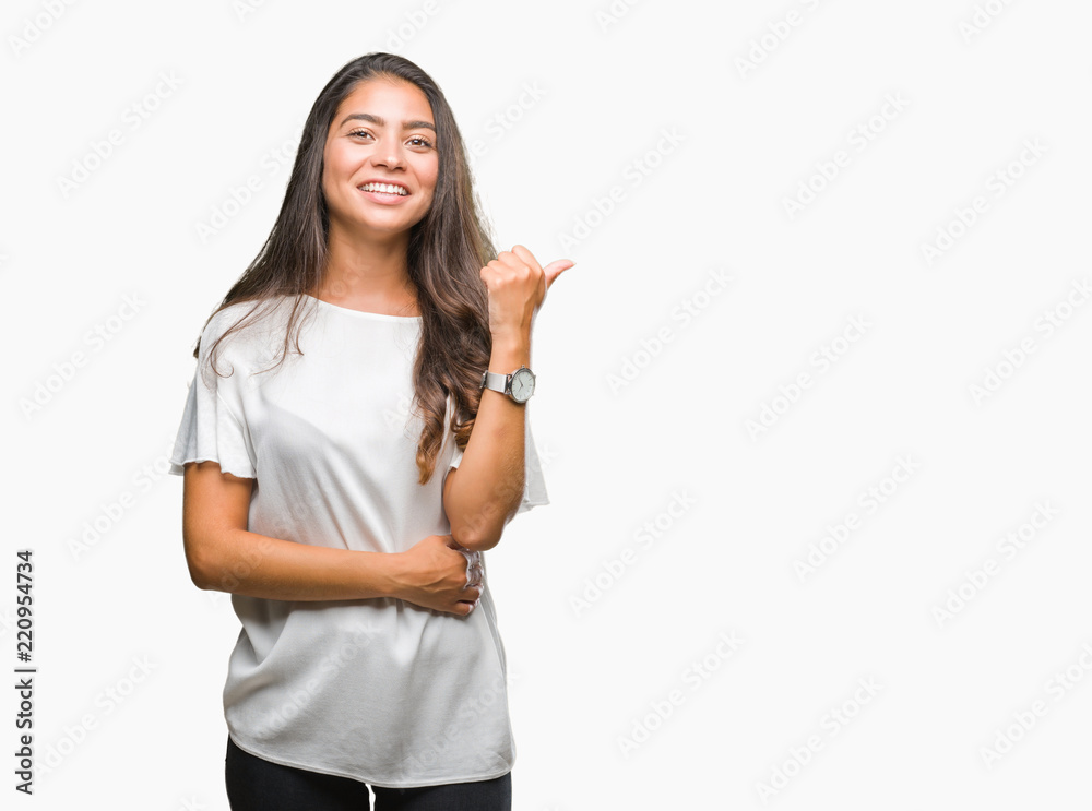 Young beautiful arab woman over isolated background smiling with happy face looking and pointing to the side with thumb up. Young beautiful arab woman over isolated background smiling with happy face looking and pointing to the side with thumb up.
