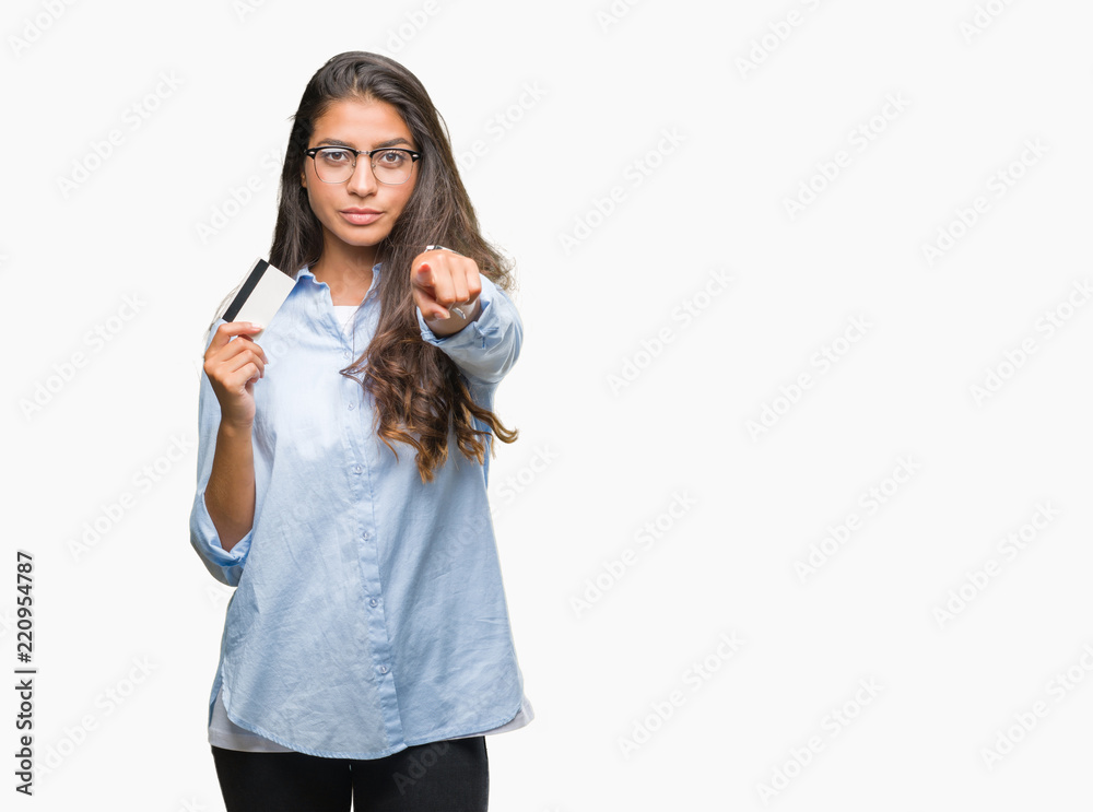 Young arab woman holding credit card over isolated background pointing with finger to the camera and to you, hand sign, positive and confident gesture from the front Young arab woman holding credit card over isolated background pointing with finger to the camera and to you, hand sign, positive and confident gesture from the front