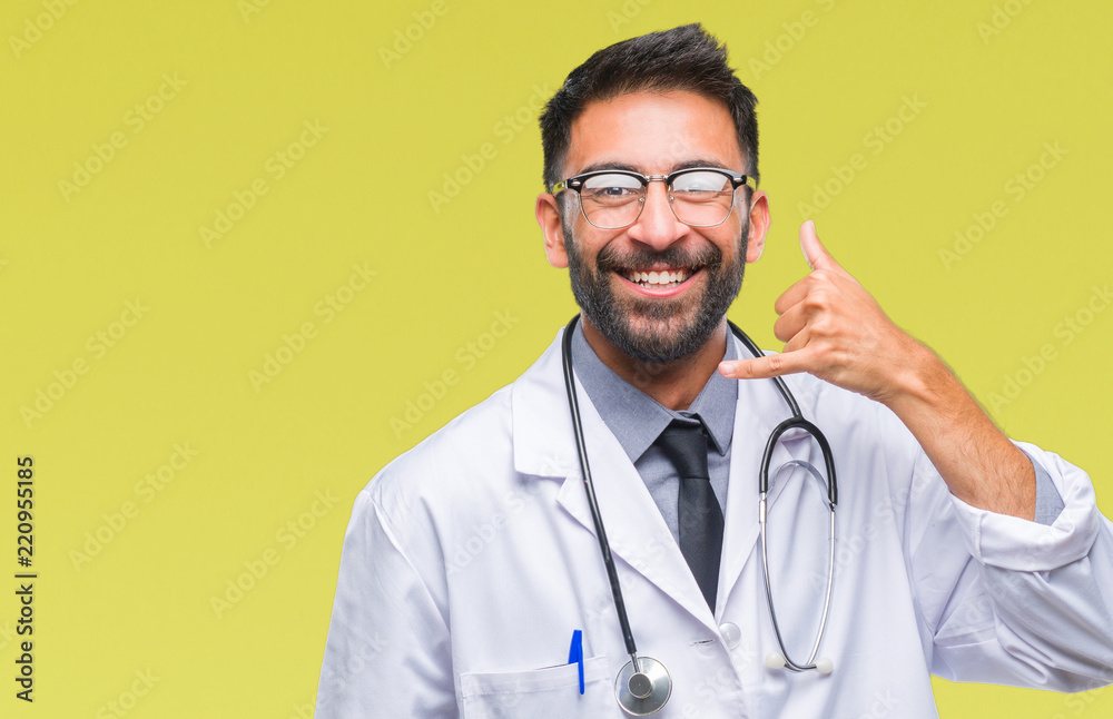 Adult hispanic doctor man over isolated background smiling doing phone gesture with hand and fingers like talking on the telephone. Communicating concepts. Adult hispanic doctor man over isolated background smiling doing phone gesture with hand and fingers like talking on the telephone. Communicating concepts.