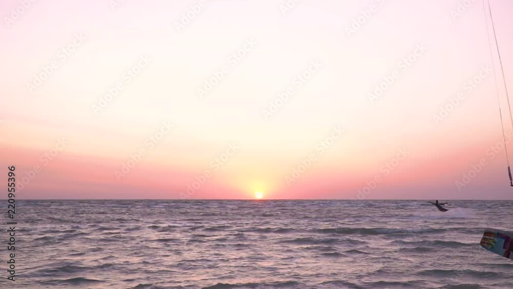 A man and a woman are kitesurfing at dawn A man and a woman are kitesurfing at dawn
